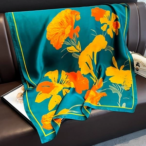 Détail d'un foulard en soie à fleurs orange sur canapé en cuir montrant le drapé du tissu