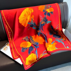 Détail d'un élégant foulard en soie rouge à motifs floraux sur un banc en cuir