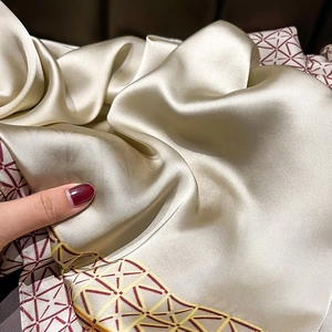 Champagne silk satin scarf with geometric border pattern and elegant draping effect