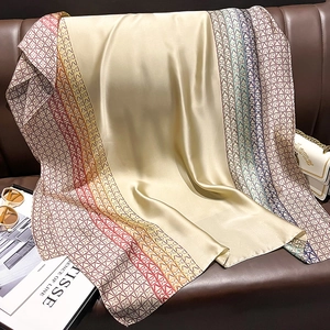 Champagne silk-like scarf with colorful geometric chain pattern on a leather background