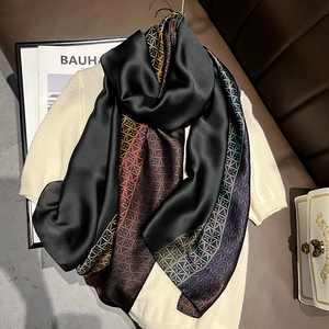 Faux silk scarf with geometric chain prints draped elegantly on a beige sweater