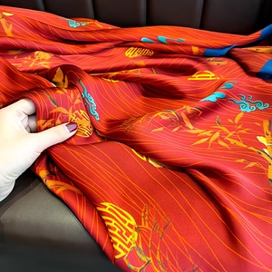 Detailed close-up of red silk satin shawl with traditional bamboo and longevity patterns