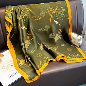 Detail showing elegant dark green silk scarf with lotus and bamboo patterns on leather