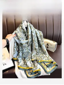 Détail d'un foulard en soie bleu clair avec motif paisley et ourlet contrasté sur pull