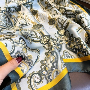 Gros plan du foulard en soie avec motifs paisley et bordures contrastées raffinées
