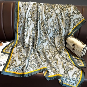 Écharpe élégante en soie à motif paisley avec bordures jaunes sur un canapé en cuir