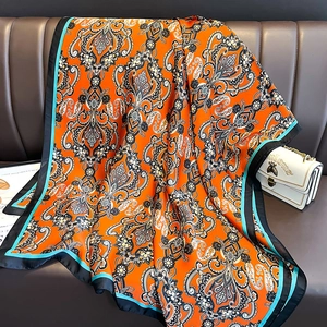 Détail d'un foulard en satin orange avec motif paisley et bordures contrastées