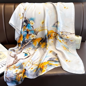 Dettaglio di sciarpa effetto seta con stampe di fiori e uccelli su divano in pelle