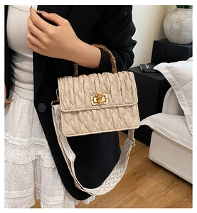 Detail of off-white quilted handbag with vintage bamboo handle and woven strap