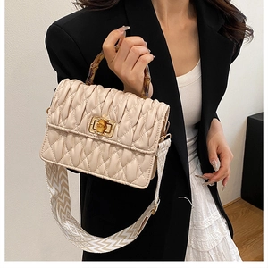 Detail of bamboo handle and quilted texture on a stylish beige crossbody square bag