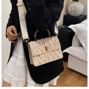 Detail of beige quilted leather crossbody bag with bamboo handle and golden turn-lock