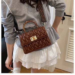 Detail of brown pleated handbag with vintage bamboo handle and geometric strap