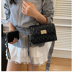 Detail of black quilted leather handbag with bamboo handle and patterned strap