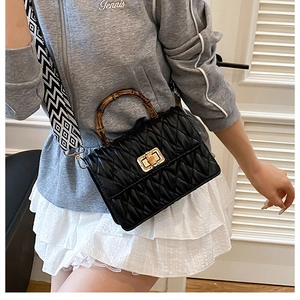 Detail of black pleated cloud bag with bamboo handle and patterned fabric strap