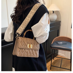 Detail of beige pleated bag featuring a bamboo handle and vintage geometric strap