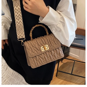 Detail of bamboo handle, pleated leather and geometric jacquard strap on a crossbody bag
