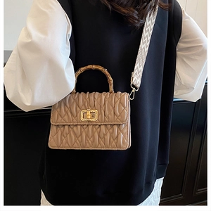 Detail of bamboo handle and quilted pleated texture on a stylish khaki crossbody bag