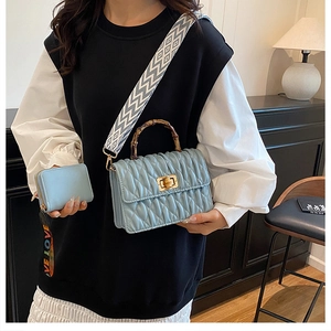 Close-up of light blue quilted bag with bamboo handle and geometric shoulder strap