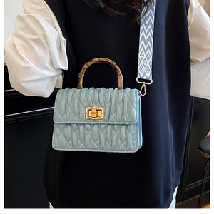 Detail of light blue quilted leather bag with bamboo handle and geometric strap