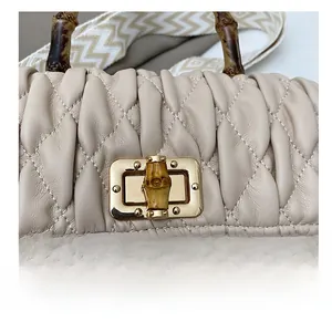 Close-up of bamboo handle, pleated leather texture, and golden metal swivel lock details