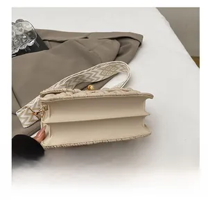 Detail view of the reinforced double-layered bottom and textured strap of the beige handbag