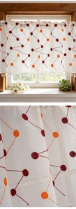 Detail of rustic white cafe curtain with red polka dot embroidery and fringe trim
