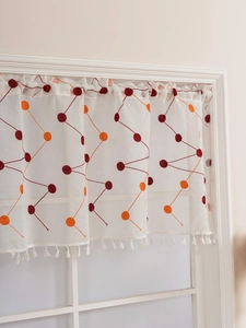 Macro detail of cream coffee curtain with red embroidery and white tassel fringe