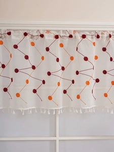 Detailed view of white cafe curtain with red polka dot embroidery and fringe trim