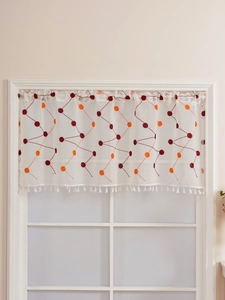 Detail of embroidered geometric patterns and white tassels on a semi-sheer cafe curtain