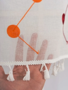 Detailed macro view of white translucent coffee curtain with orange polka dot embroidery