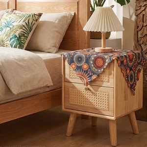 Detail of bohemian floral table runner on a Nordic wooden nightstand with rattan drawers