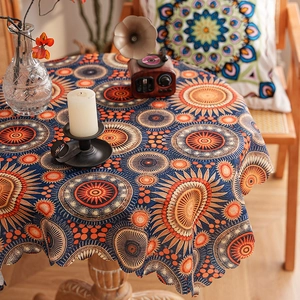 Detail of bohemian mandala cotton linen tablecloth with intricate wavy edge on a wooden table