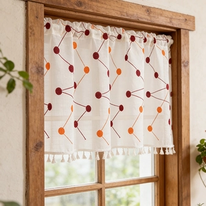 Bohemian cafe curtain with orange polka dots and tassels on a wooden window frame