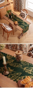 Detail of scalloped edge table runner with golden feather patterns on dark green fabric