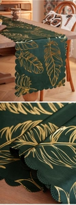 Detail of dark green velvet table runner with gold feather pattern and scalloped edge