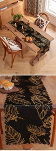Detail of black table runner with golden feather patterns and wavy scalloped edges