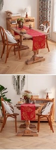 Detailed view of red table runner featuring golden feather patterns and wavy edges