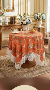 Detail of orange floral mink velvet tablecloth with white lace edges in retro style