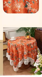 Macro view of caramel round tablecloth with white floral crane patterns and lace trim