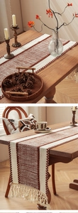 Detail of bohemian striped table runner featuring handmade braided tassels and texture