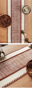 Detail of bohemian woven table runner with tassels on a rustic wooden dining table