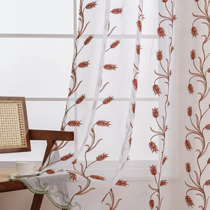 Sheer white curtains with rustic wheat embroidery and green scalloped edges in sunlight