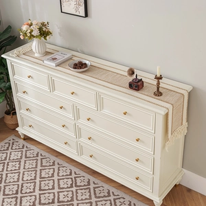 Rustic jute table runner with cream fringe tassels on a white cabinet surface