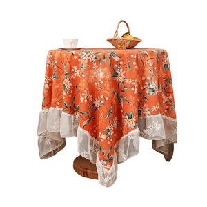 Orange floral crane fabric tablecloth with lace edge on a round wooden table