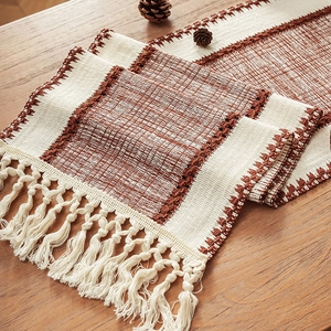 Bohemian striped woven table runner with tassels on a wooden surface with pine cones