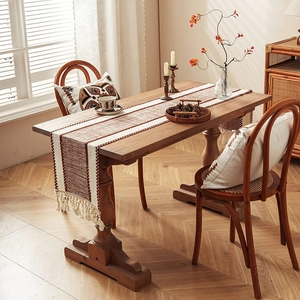Bohemian woven table runner with geometric stripes and tassels on a wood dining table