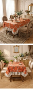 Detail of vintage French floral tablecloth with orange botanical prints and lace borders