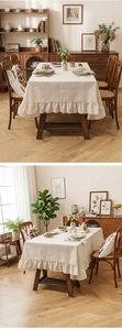 Detail of elegant beige linen tablecloth with ruffled edges on a wooden dining table