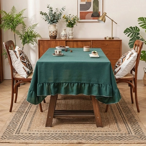 Dark green linen tablecloth with elegant ruffled edges on a rectangular table