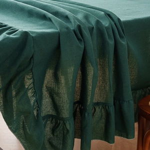 Solid dark green linen tablecloth with elegant ruffled edges for a modern dining table